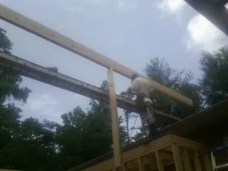Carpenter setting a ridge beam over a new addition frame — Ice Dam Removal by Roofing Brothers in Glenburn