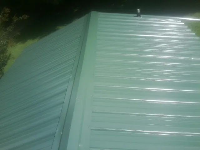 New green metal panels meeting at the ridge of a roof — Flat Roof Repair work by our crew in Glenburn