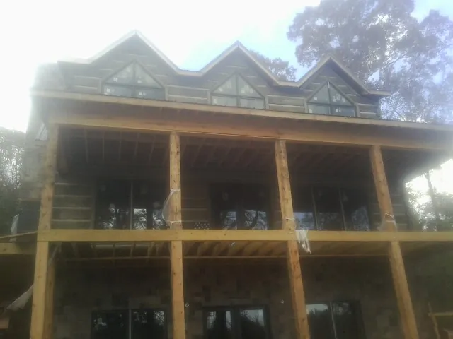 Dormers and porch framing on a large log home under construction — Roof Coating work by our crew in Glenburn