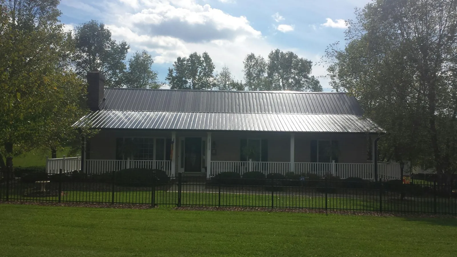 Gray metal roof on a brick ranch with a full width front porch — Gutter Guard Installation work by our crew in Glenburn