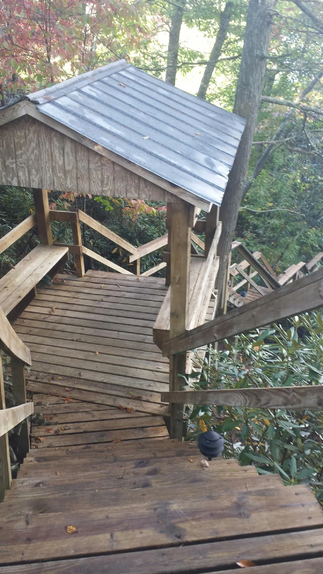 Metal roofed shelter over wooden steps on a wooded walkway — Skylight Repair & Installation work by our crew in Glenburn
