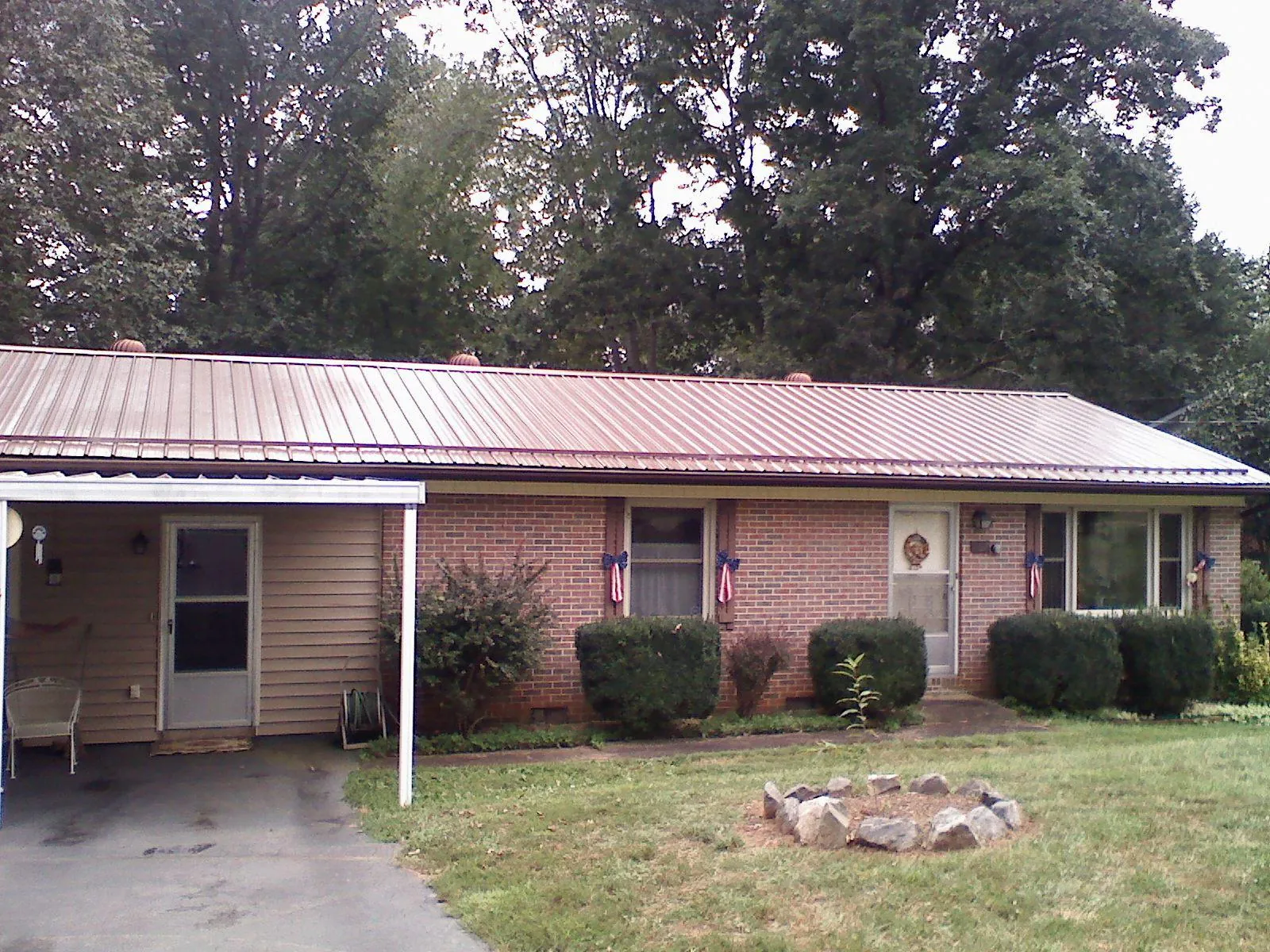 Bronze metal roof and carport on a brick ranch home — Roof Repair work by our crew in Glenburn