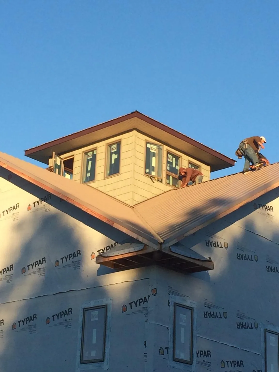 Roofers working around a rooftop cupola on a new metal roof at sunset — Roof Waterproofing in Glenburn by Roofing Brothers